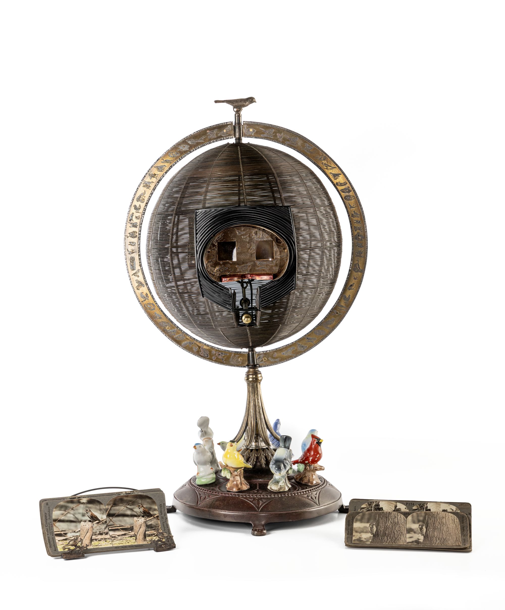 Globe- like sculpture with birds made out of steel, bronze, wood, brass, ceramic, and stereocards.